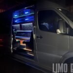 Open side door at night showing the lit-up entryway of the Mercedes Sprinter 15-passenger party bus.