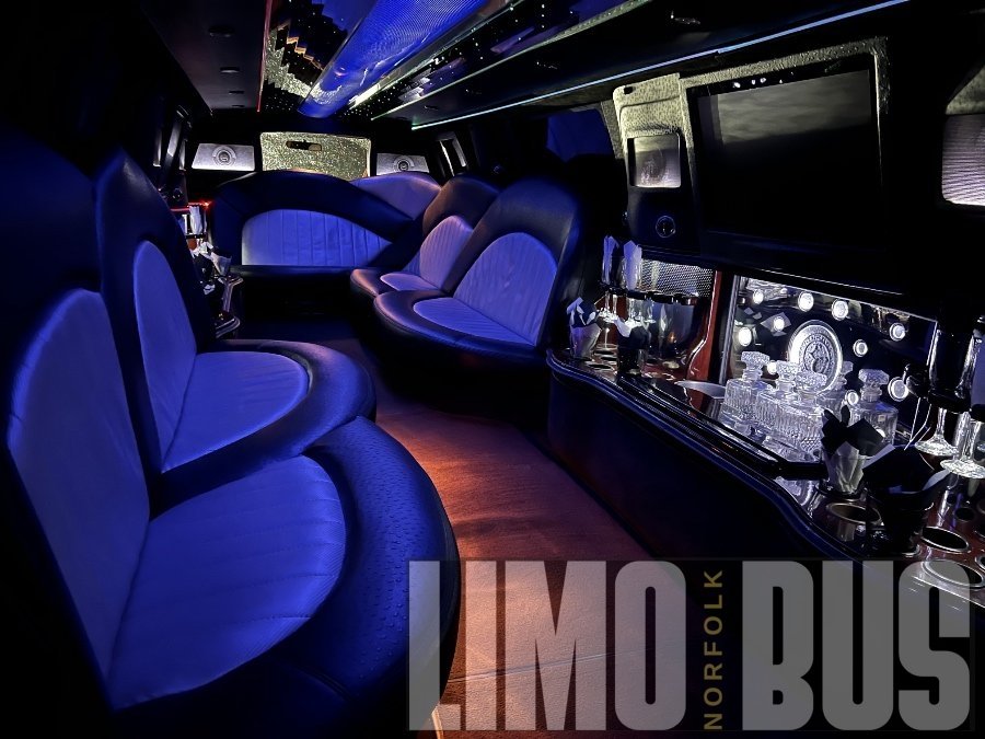 Elegant 22-passenger SUV limousine interior with plush leather seating, LED lighting, and crystal bar setup, available from Limo Bus Norfolk.