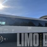Side profile of a white 38-passenger party bus under the sun, highlighting its modern design for Norfolk events and group rentals.