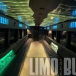 Spacious 50-passenger party bus interior with yellow and blue illuminated ceiling panels, luxury seating, and full entertainment setup.