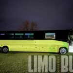 Side view of a 50-passenger luxury party bus under night lights, available for large group travel and celebrations in Norfolk.