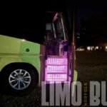 Illuminated steps leading into a 50-passenger party bus at night, showcasing luxury features for Norfolk events.